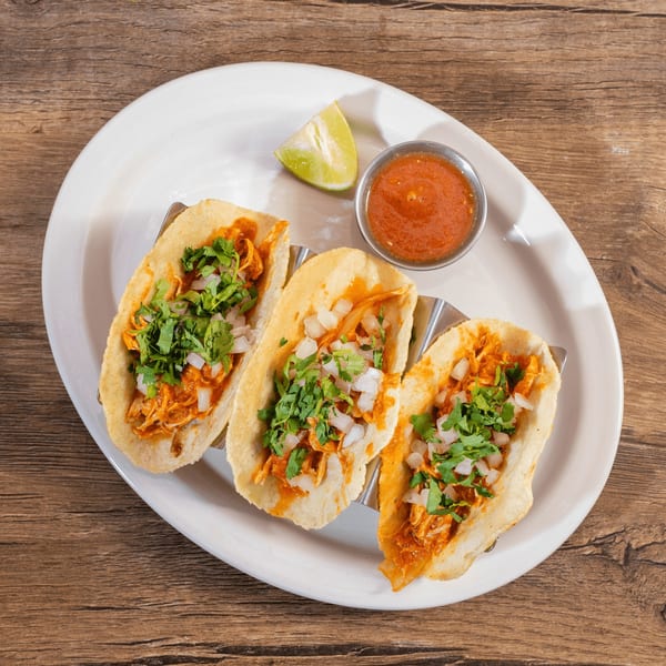 Three Don Julio's chicken tacos with cilantro and onions, served with salsa and lime.