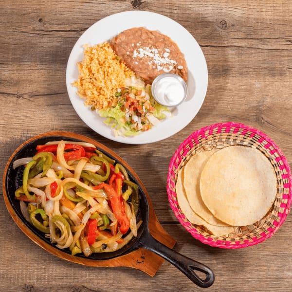 Don Julio's Mexican fajitas with colorful bell peppers and onions, served with rice, beans, and tortillas.