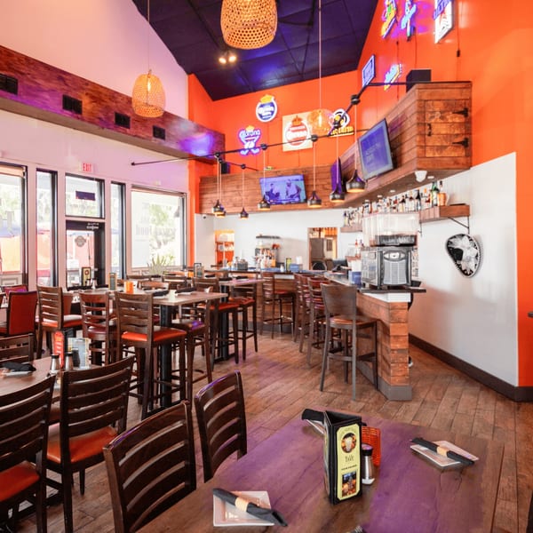 Don Julio's vibrant Mexican restaurant interior with orange walls, wooden tables, bar, and neon signs.