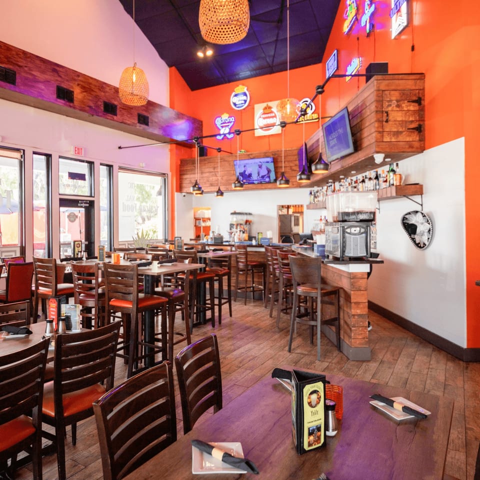 Don Julio's vibrant Mexican restaurant interior with orange walls, wooden tables, bar, and neon signs.