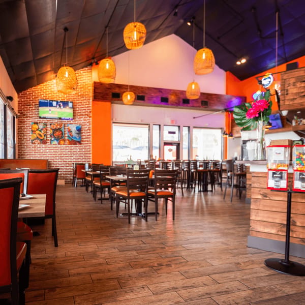 Spacious interior of Don Julio's Mexican restaurant with brick walls, orange accents, and wooden tables and chairs.