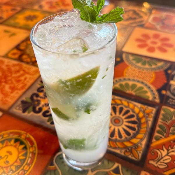 A refreshing mojito with lime and mint on a colorful, patterned Mexican tile table.