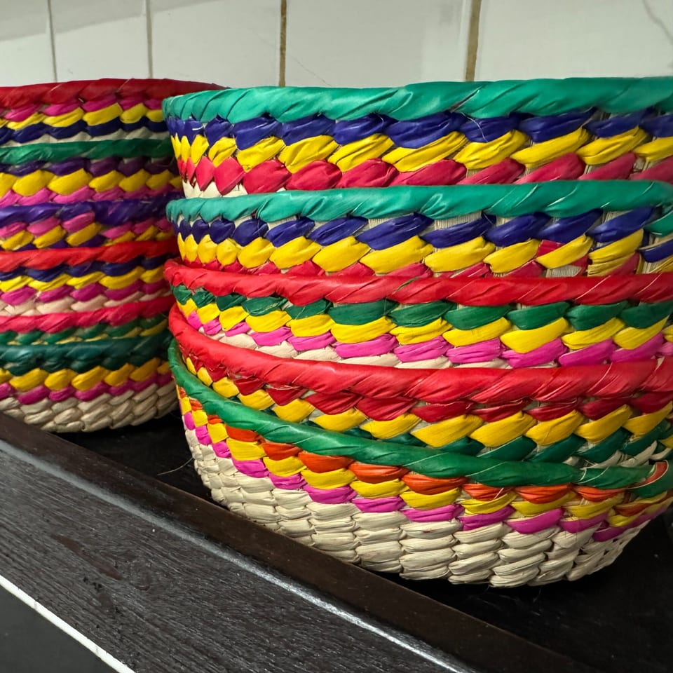 Two colorful woven baskets with red, green, yellow, and blue stripes, on a dark wooden surface.