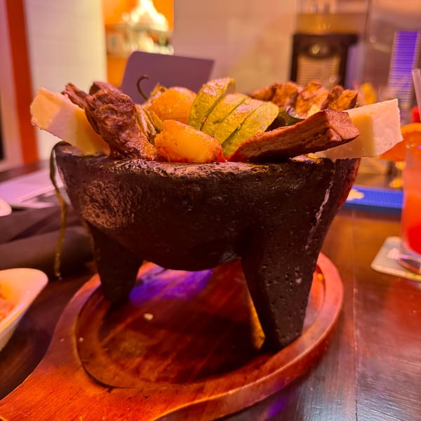 Don Julio's molcajete with grilled meats, cheese, avocado, and peppers on a wooden tray.