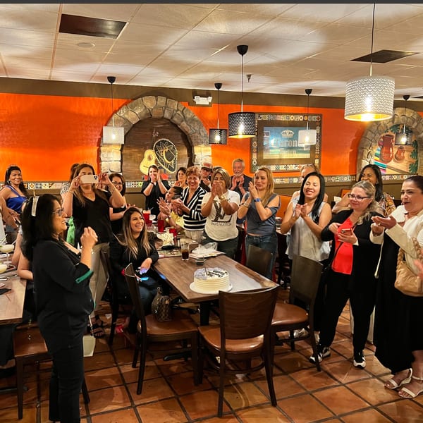 A group of people celebrating with a cake at Don Julio's Mexican restaurant, clapping and smiling.